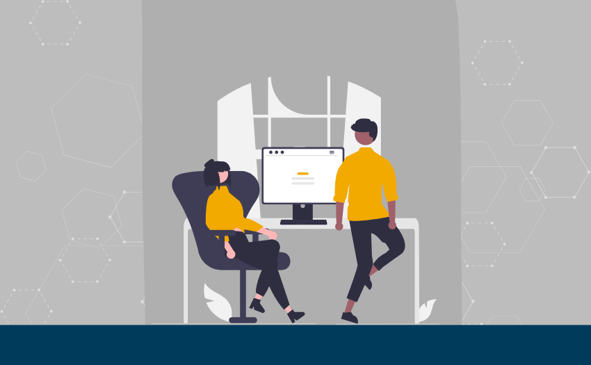 Two colleagues discuss something in front of a computer screen in a modern office setting, suggesting active collaboration and engagement.